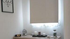 Makuuhuone, jossa on sänky, yöpöytä, jossa on kello, kehystetty inspiroiva sitaatti, riippuvalaisin ja ikkuna, josta on näkymä.