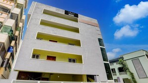 A multi-story building with balconies, a gated entrance, and a clear sky. - Deluxe y Stay Home Stay (Tirupati)