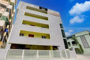A multi-story building with balconies, a gated entrance, and a clear sky. - Deluxe y Stay Home Stay (Tirupati)