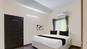 A hotel room with a bed, a door, an air conditioning unit, and a window with curtains. - Deluxe y Stay Home Stay (Tirupati)