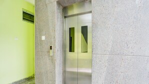 An elevator with a metallic finish, a green wall, and a speckled floor. - Deluxe y Stay Home Stay (Tirupati)