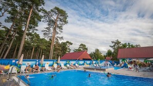 Una piscina con sillas de descanso y un mural, rodeada de árboles altos.