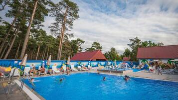 A swimming pool with lounge chairs and a mural, surrounded by tall trees.