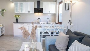 Una sala de estar moderna con un sofá, una mesa de centro con velas y una cocina al fondo.