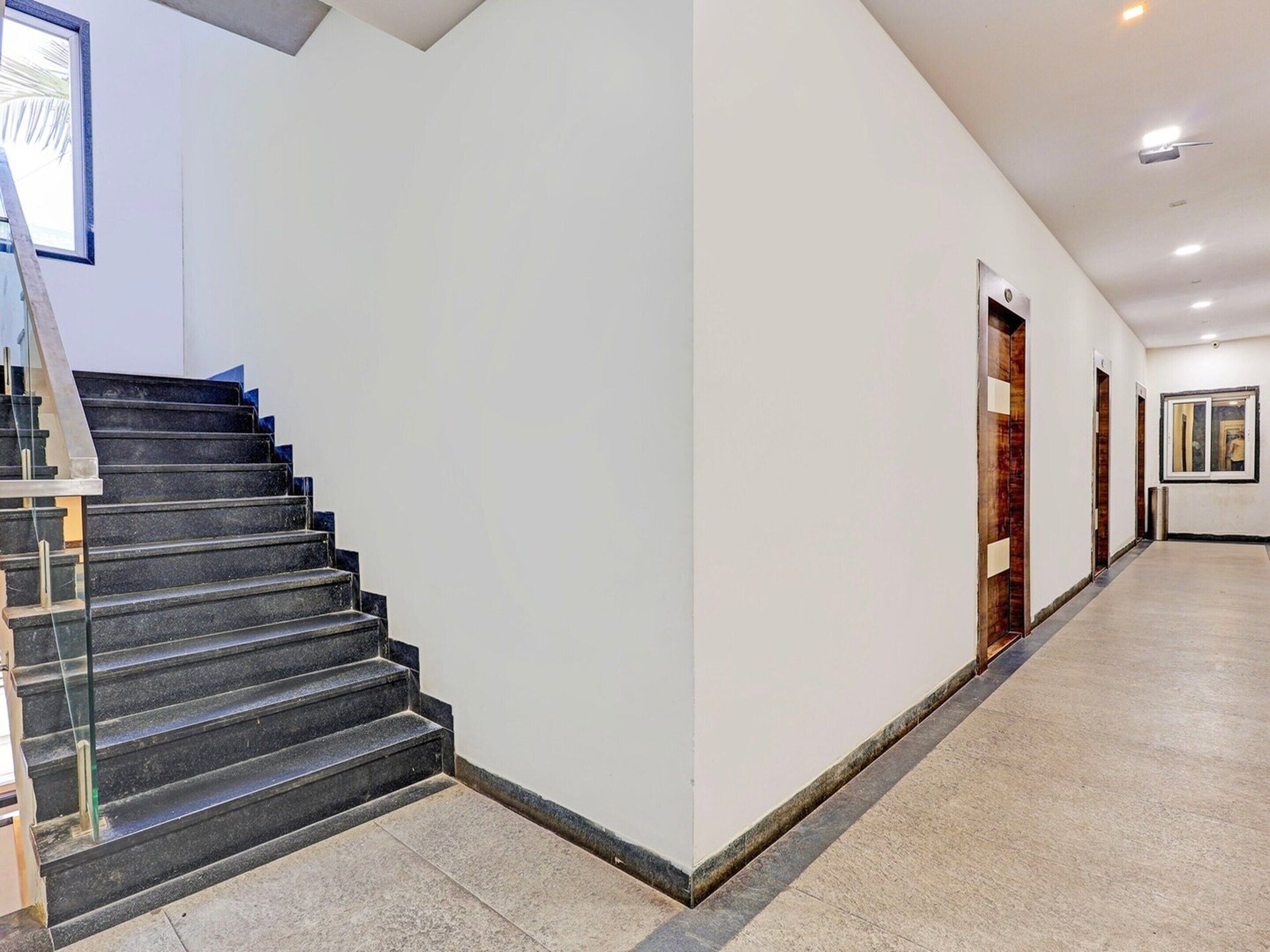 Un intérieur moderne avec un escalier, un couloir et une porte.