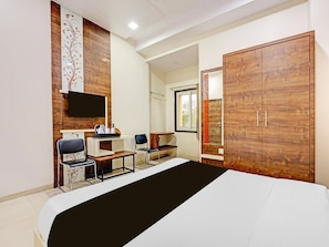 A bedroom with a bed, a desk, a chair, a wardrobe, and a TV.