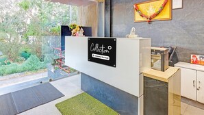 Un área de recepción con un separador de vidrio, un cartel que indica que es punto de recogida de servicios de la empresa, una pequeña estatua y un cuadro en la pared.