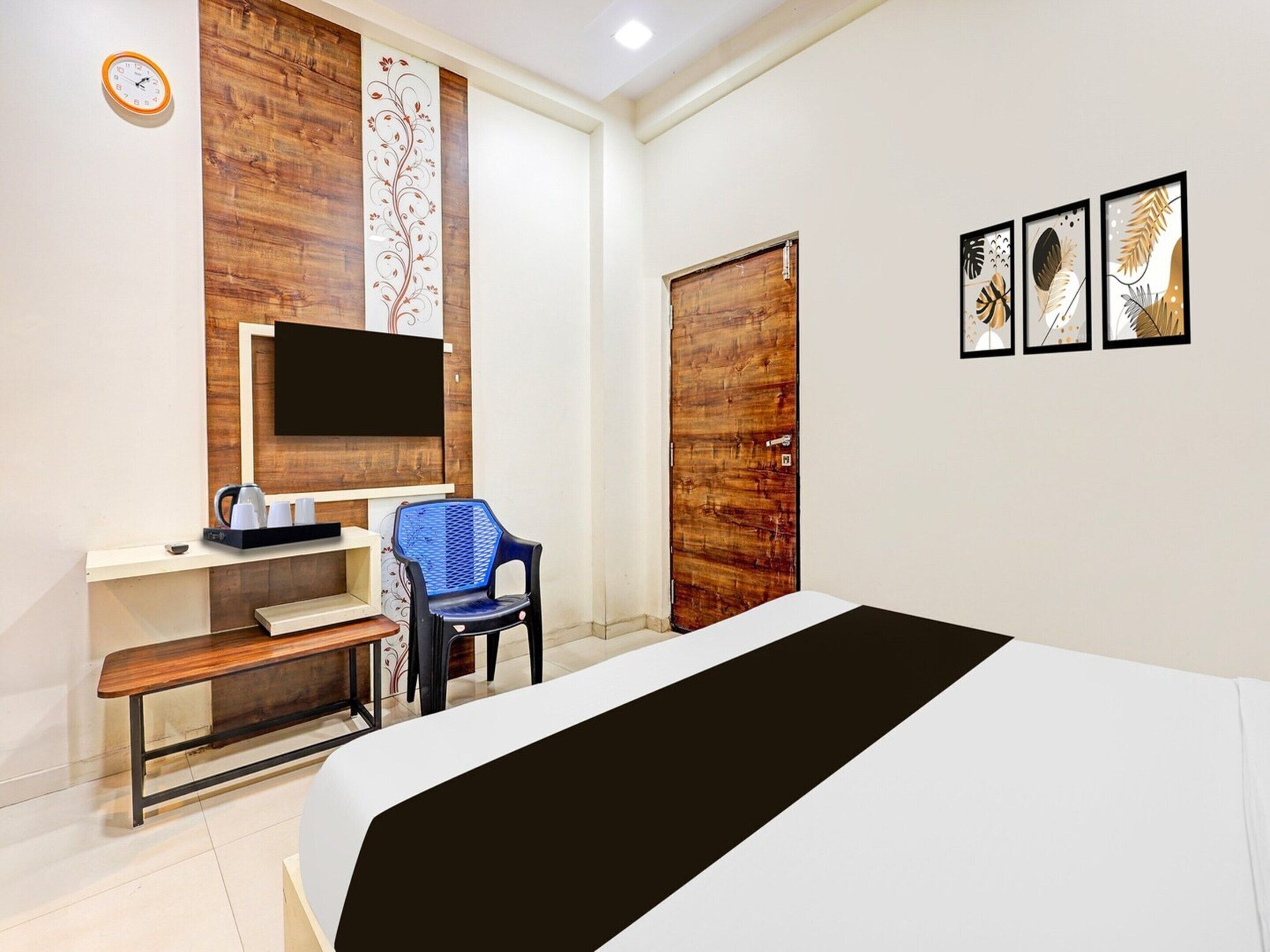 Une chambre d’hôtel avec un lit, un bureau avec un ordinateur, une chaise, une télévision et une porte en bois.