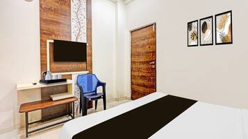 Une chambre d’hôtel avec un lit, un bureau avec un ordinateur, une chaise, une télévision et une porte en bois.