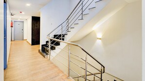 Een modern interieur met een trap, houten vloeren en een deur met een brandblusser.