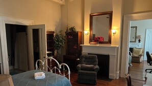 Un dormitorio con una cama, una silla, una chimenea y un espejo.
