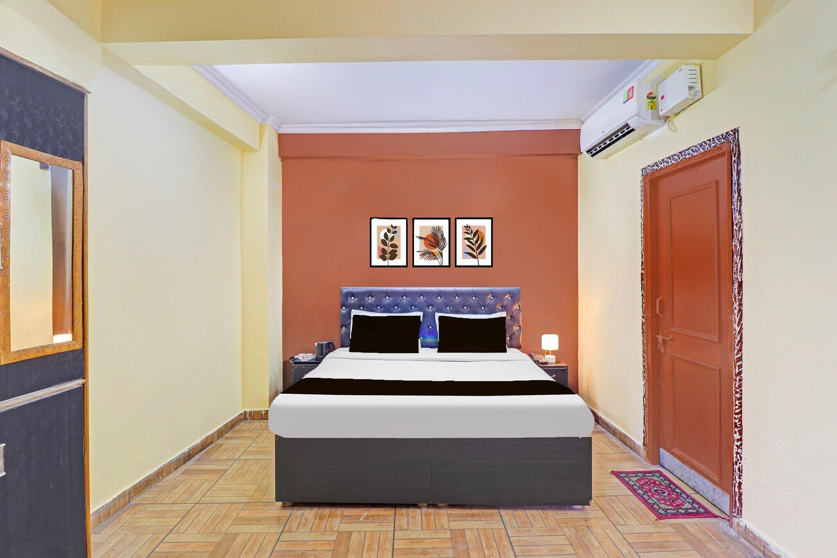 A bedroom with a bed, a nightstand, a wall-mounted air conditioner, and a door.