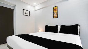 A modern hotel room with a large bed, a framed picture on the wall, and a decorative piece above the bed. - Collection O Andheri Near Mumbai Airport (Mumbai)