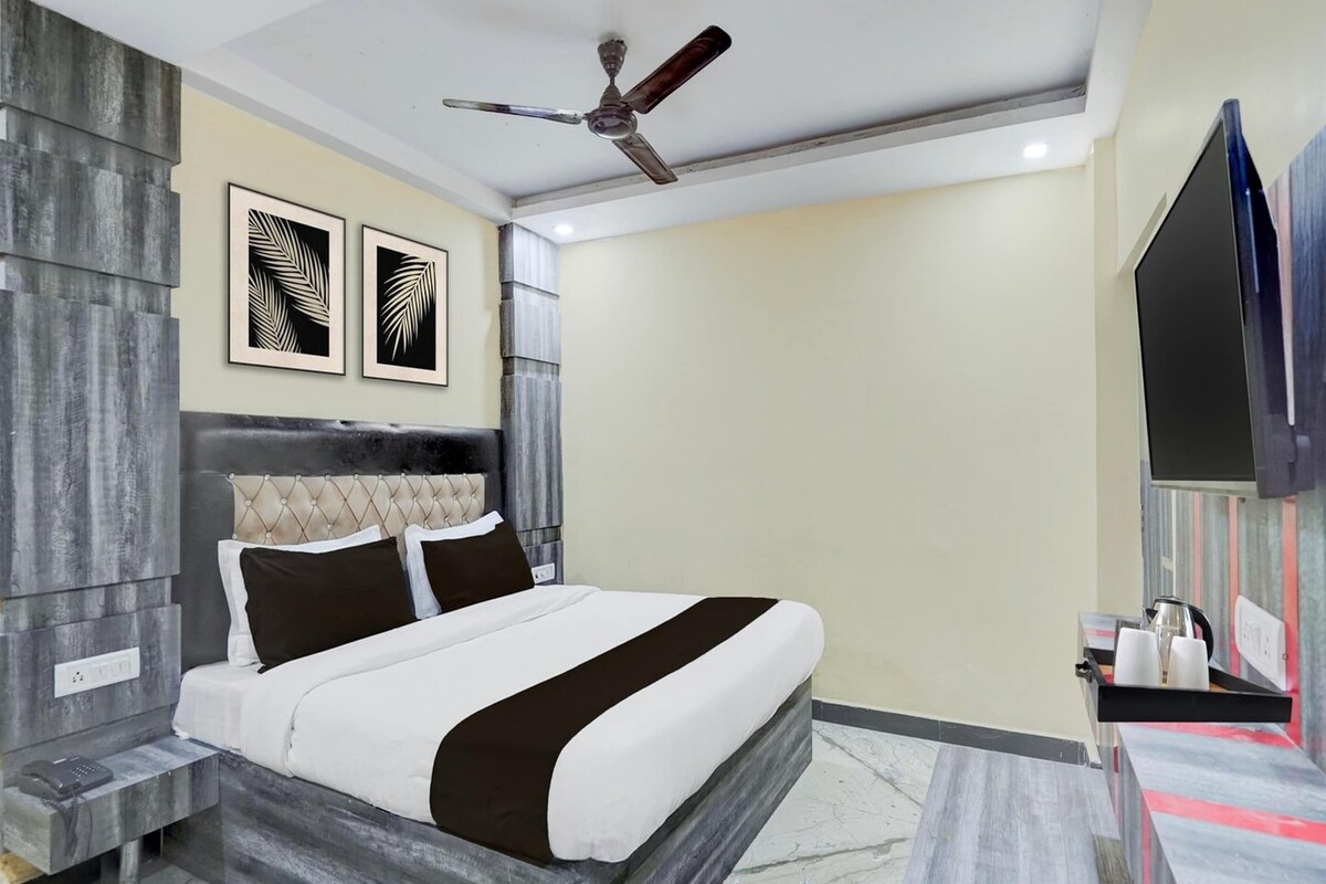 A modern bedroom with a bed, a ceiling fan, and artwork on the wall.