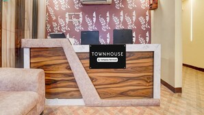 A reception desk with a 'Townhouse' sign, a mounted air conditioner, and a patterned wall. - Super Deluxe Roomamba Palace (Prayagraj)