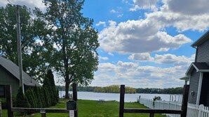 A gravel path leading to a fenced area with a lake view, a wooden fence, and a building with a sloped roof.