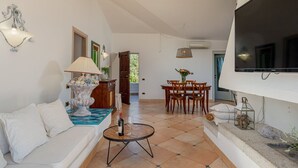 A living room with a sofa, coffee table, dining table, and chairs. - Villa Junia by Klodge, pool & seaview in San Pantaleo (San Pantaleo)