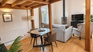 En moderne stue med træloft, spisebord med stole, sofa, fjernsyn og pejs.