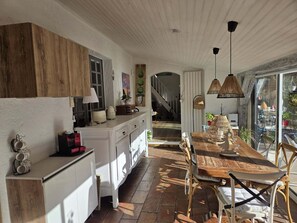 A kitchen with a wooden cabinet, a dining table with chairs, and a staircase leading to another room. - Charming riverside house with pool and private riverbank (Tourrettes-sur-Loup)