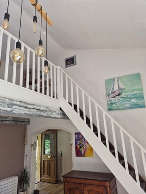 A staircase with white railings, a sailboat painting, and a bookshelf in the background. - Charming riverside house with pool and private riverbank (Tourrettes-sur-Loup)