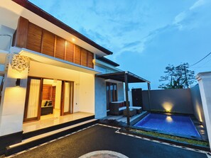 A modern house with a swimming pool, a covered patio, and a well-lit entrance. - Bali Lovina Karuna Villa near beach (Kabupaten Buleleng)