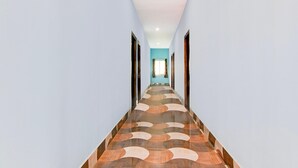 Un couloir avec un sol à motifs, des murs bleu clair et une porte au fond.