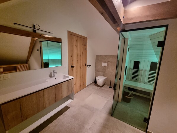 A modern bathroom with a wooden vanity, a glass shower enclosure, and a visible toilet.