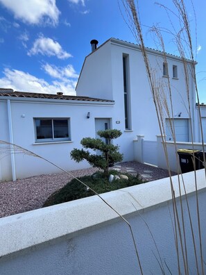 A modern white building with a chimney, a small tree, and a gravel pathway. - Quiet new house 2.5 km from the sea, the Zoo and the resort of La Palmyre (Saint-Augustin)