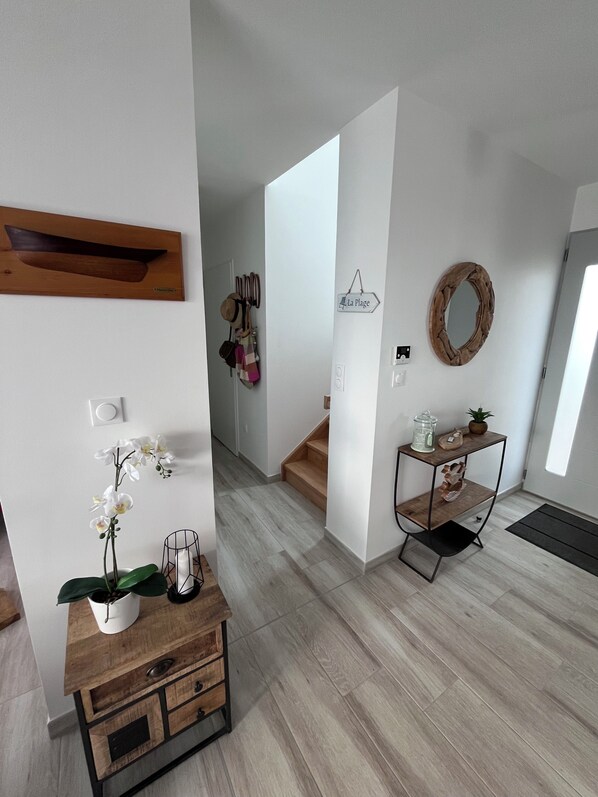 A modern interior with a wooden cabinet, a mirror, a staircase, and a hallway leading to another room. - Quiet new house 2.5 km from the sea, the Zoo and the resort of La Palmyre (Saint-Augustin)