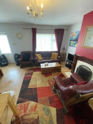 A living room with a sofa, a coffee table, a fireplace, and a rug.