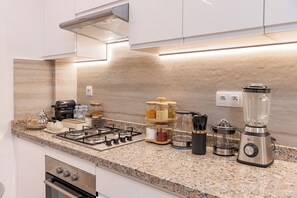 A modern kitchen with granite countertops, a gas stove, a blender, and various kitchen appliances. - Modern pearl in the heart of Guéliz (Marrakech)
