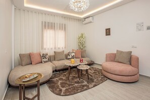 A modern living room with a sectional sofa, a round coffee table, and a small side table. - Modern pearl in the heart of Guéliz (Marrakech)
