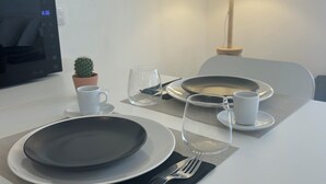 A neatly set dining table with plates, cutlery, and a small potted plant. - Modern Studio with Private Patio near Cascais and Sintra (Alcabideche)