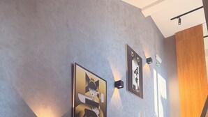 A staircase with a modern design, a wall with two framed artworks, and a potted plant. - XIO Apartments (Bar)