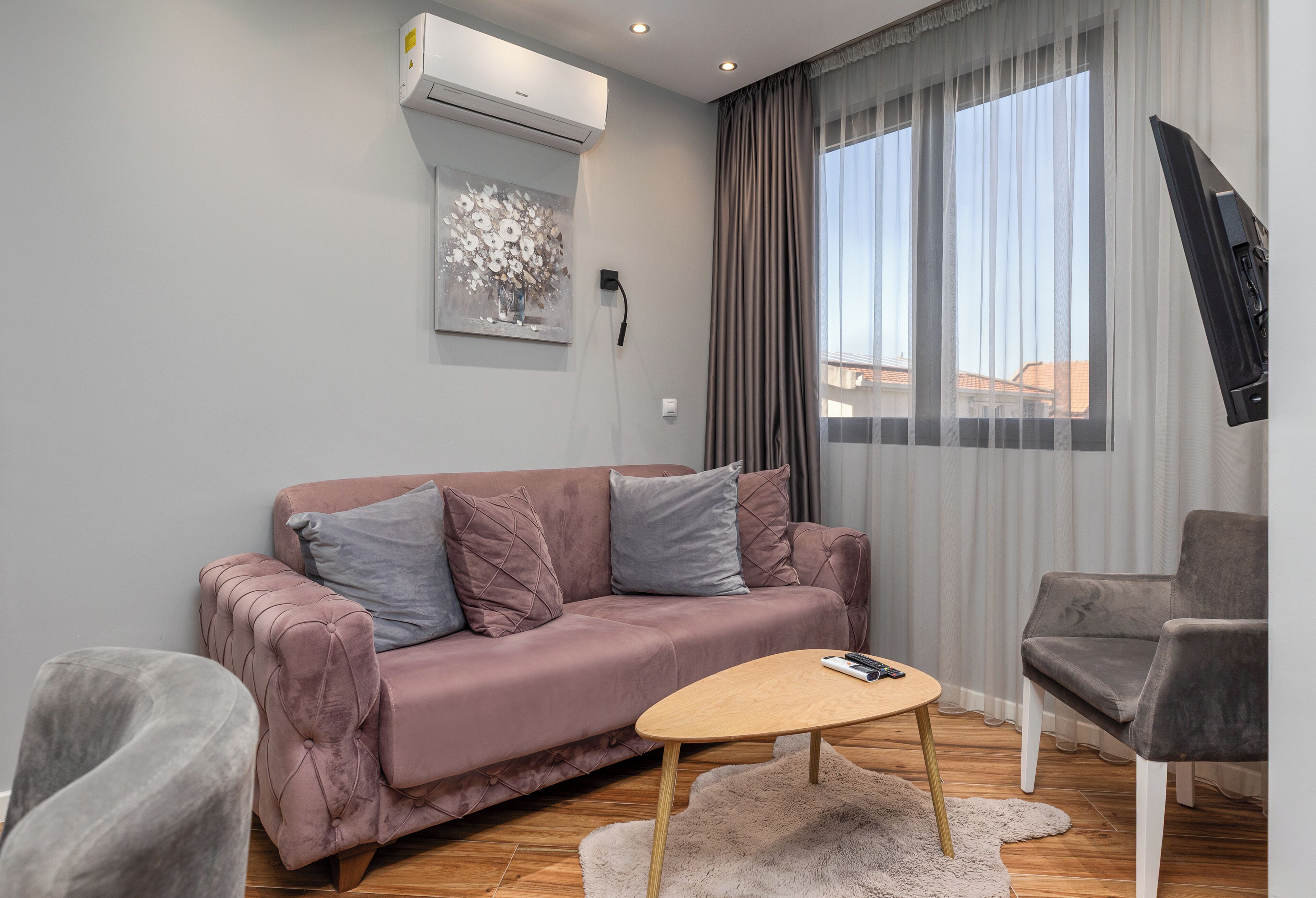 A modern living room with a sofa, a coffee table, a TV, and a window with curtains.