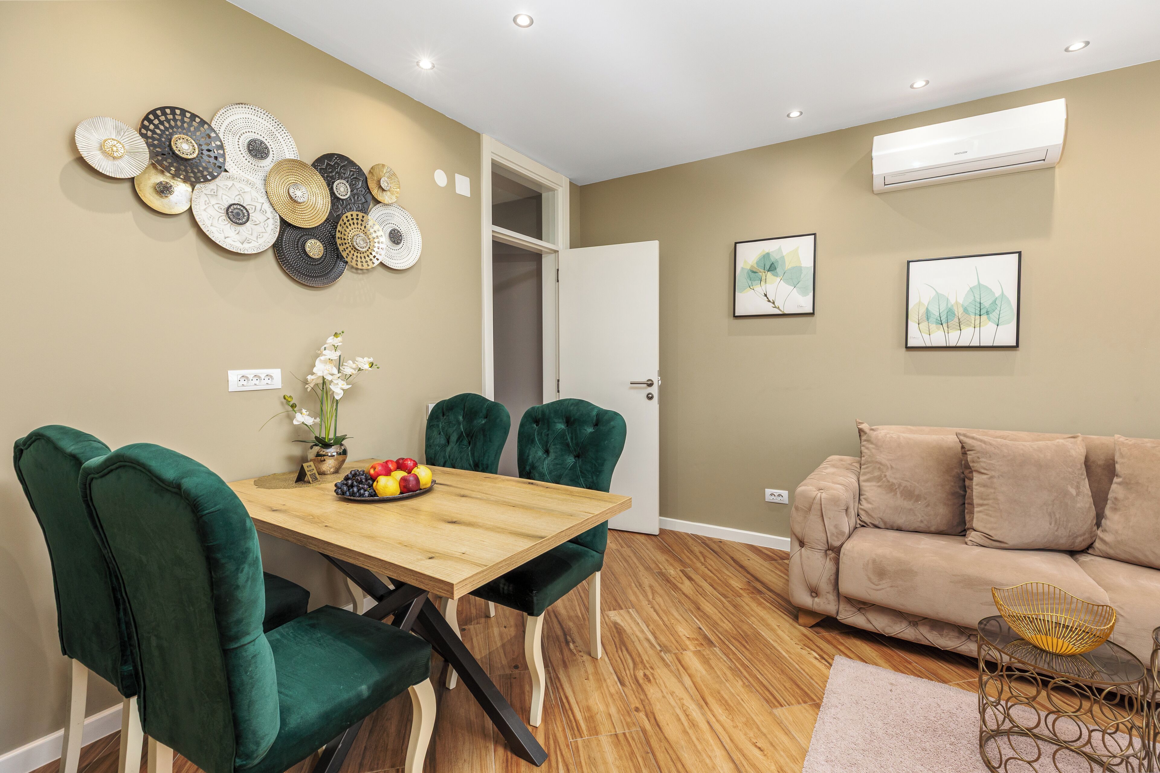 A dining area with a wooden table, green upholstered chairs, and a beige sofa.