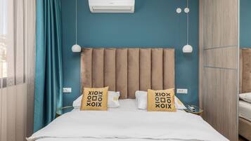 A bedroom with a bed, two bedside lamps, an air conditioning unit, and a window with curtains.