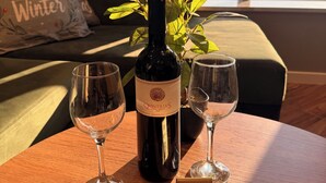 A table with a wine bottle, two wine glasses, a potted plant, and a QR code sign. - XIO Apartments (Bar)