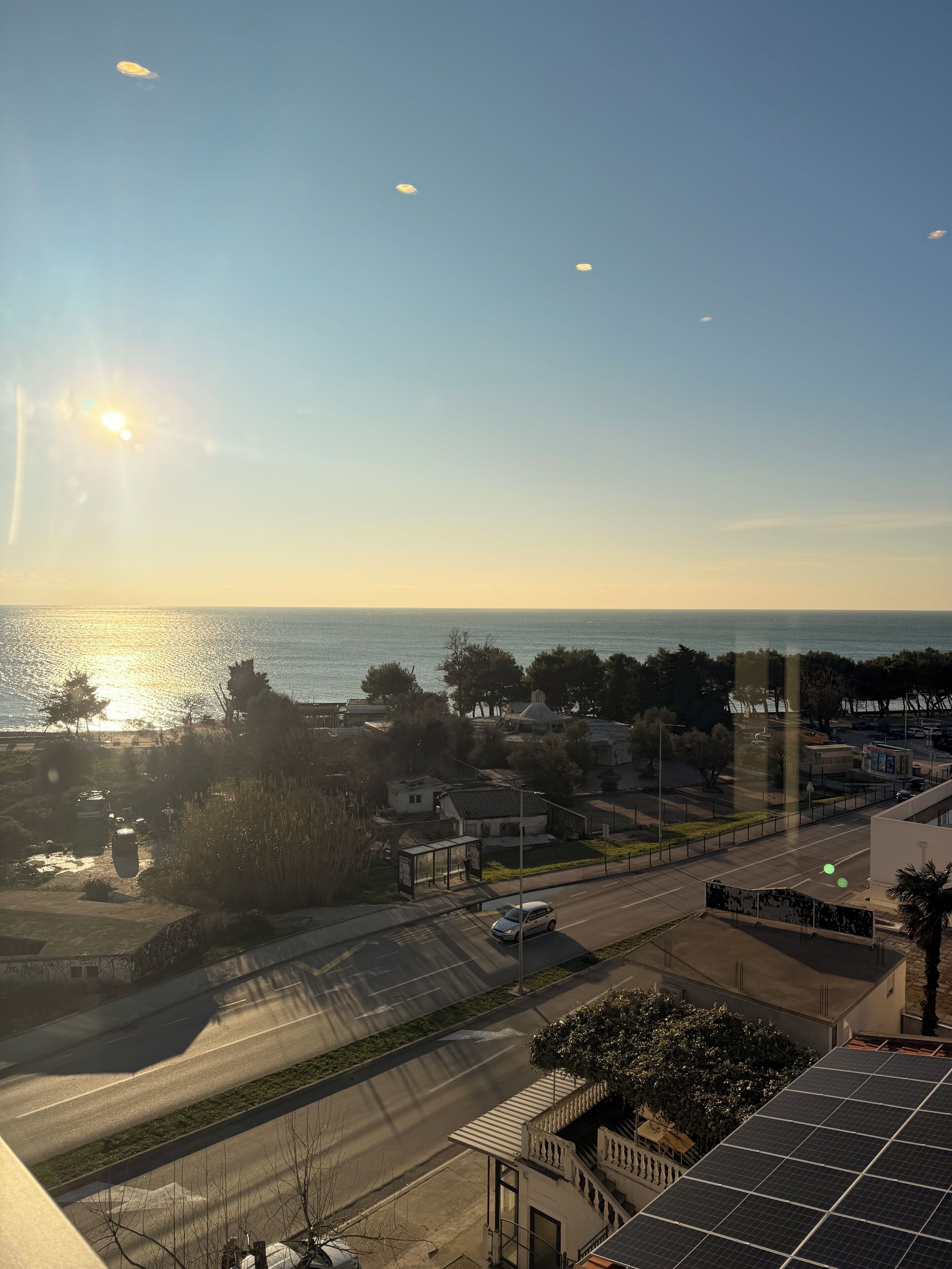 Une vue côtière avec une route, un arrêt de bus et un bâtiment équipé de panneaux solaires.
