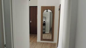 Un pasillo con piso de madera, techo oscuro y un espejo con rayas verticales.