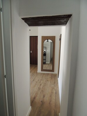 A hallway with wooden flooring, a dark ceiling, and a mirror with vertical stripes. - Central Genoa Apartment - 2 Bedrooms near Aquarium, University & Old Town (Genova)