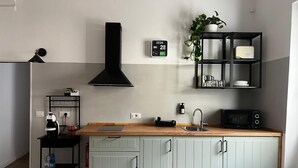 Una cocina moderna con microondas integrado, extractor de aire negro, un lavamanos y un calendario en la pared.