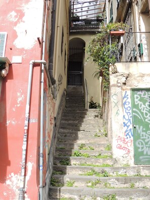A narrow stairway leading to a door with graffiti, surrounded by buildings with balconies and plants. - Central Genoa Apartment - 2 Bedrooms near Aquarium, University & Old Town (Genova)
