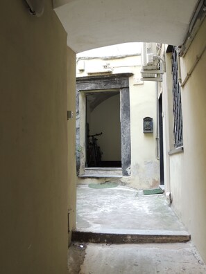 A narrow alleyway leading to a building entrance with a bicycle parked inside. - Central Genoa Apartment - 2 Bedrooms near Aquarium, University & Old Town (Genova)