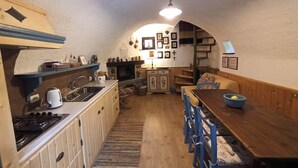 A compact kitchen with a stove, sink, and wooden dining table.