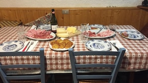 A dining table set with plates of food, glasses, and a bottle of wine.