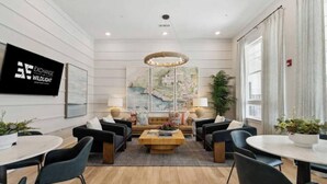 A modern hotel lobby with a central seating area, a large painting on the wall, and a sign for 'EXCHANGE WILDLIGHT'. - Family Cinema Escape · Salt Pool · Gym · Sleeps 8 (Yulee)