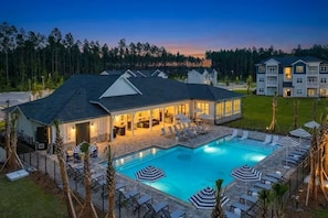 A hotel with a swimming pool, lounge chairs, and umbrellas.