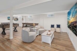 Een ruime woonkamer met een pooltafel, comfortabele zithoek en een groot schilderij.