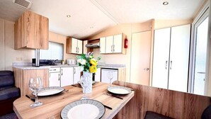 Una cocina compacta con armarios de madera, una mesa de comedor para cuatro personas y un banco empotrado.